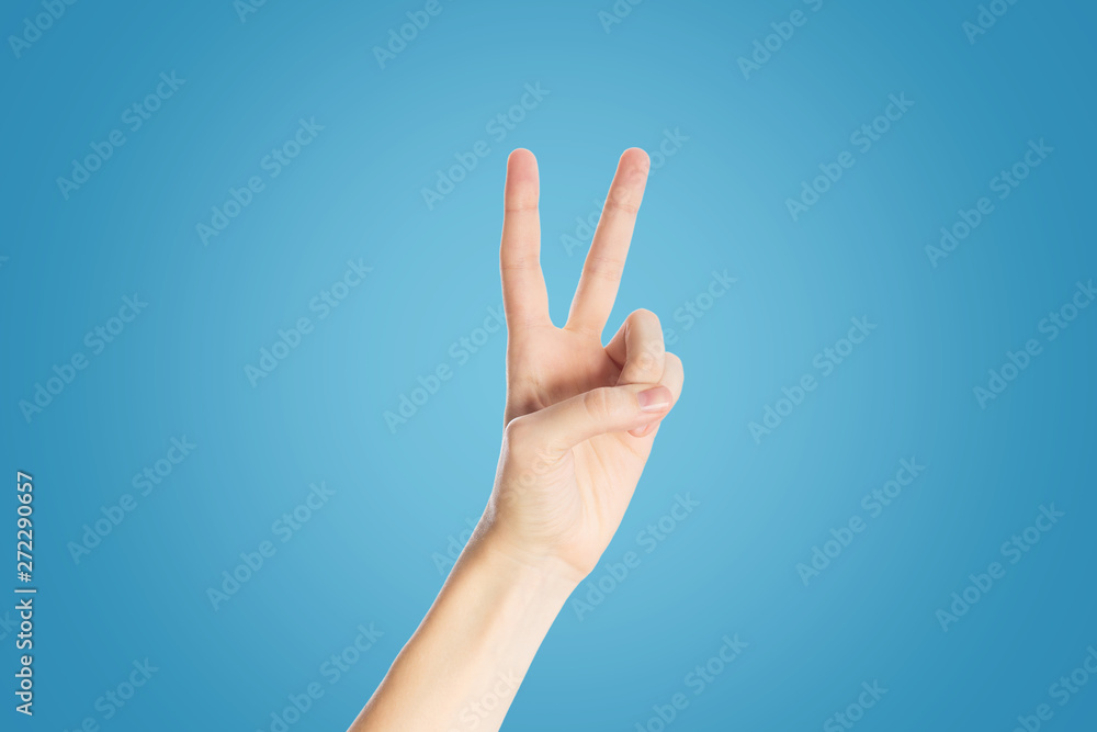 Positive gesture on a blue background. Hand show viktory sign, close up Positive gesture on a blue background. Hand show viktory sign, close up