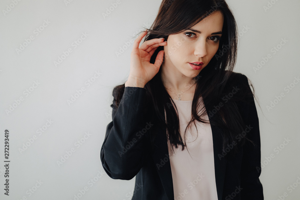 Young attractive emotional girl in business-style clothes on a plain white background in an office or audience Young attractive emotional girl in business-style clothes on a plain white background in an office or audience
