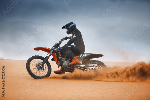 Rider on a cross-country endure motorcycle go fast at the desert