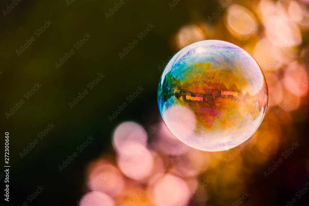 colourful soap bubble floating against a mainly dark background with a streak of light bubble bokeh. There are building reflections in the bubble colourful soap bubble floating against a mainly dark background with a streak of light bubble bokeh. There are building reflections in the bubble