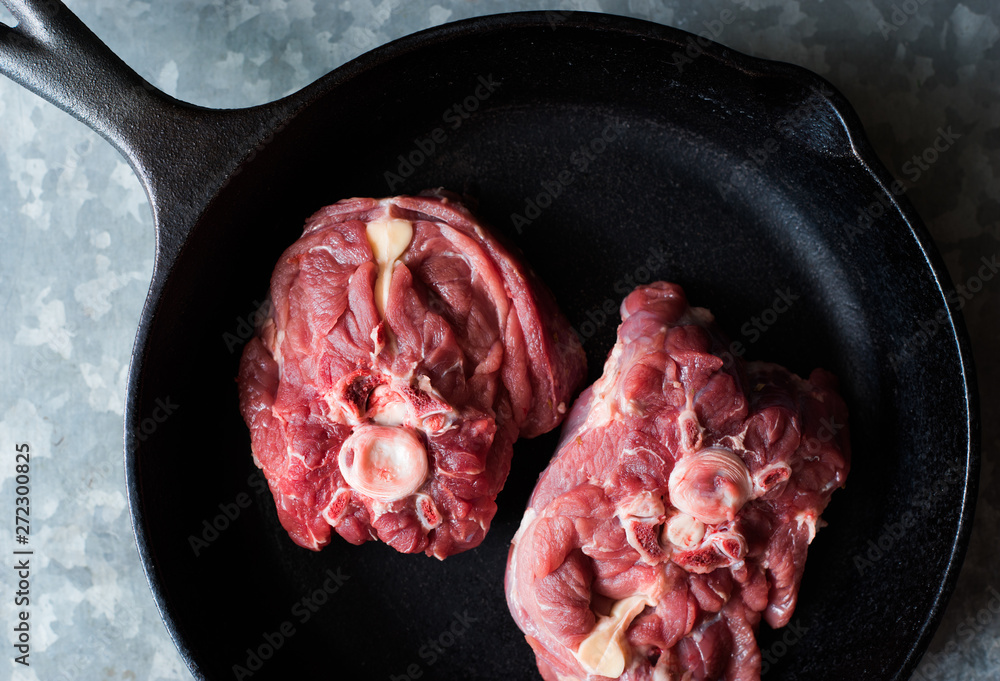Two pieces of raw lamb meat in a pan top view space for text