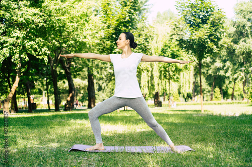 Beautiful young woman doing yoga in park. Relaxing and meditating while being surrounded by nature in summer park © My Ocean studio