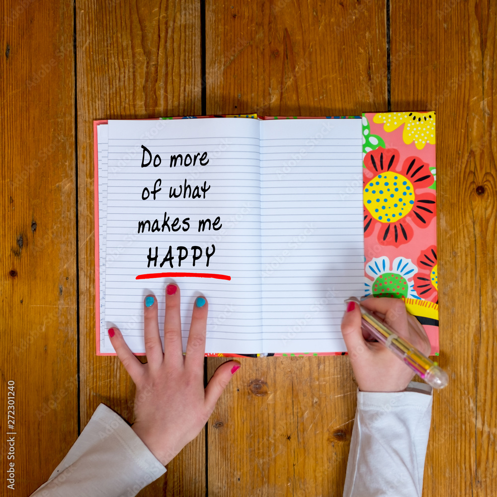Young girl writing the words ‘do more what makes me happy’ in a vintage ...