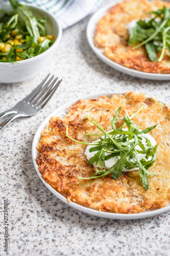 Potato rosti with corn and rocket salad served on a gray background. Traditional swiss dish