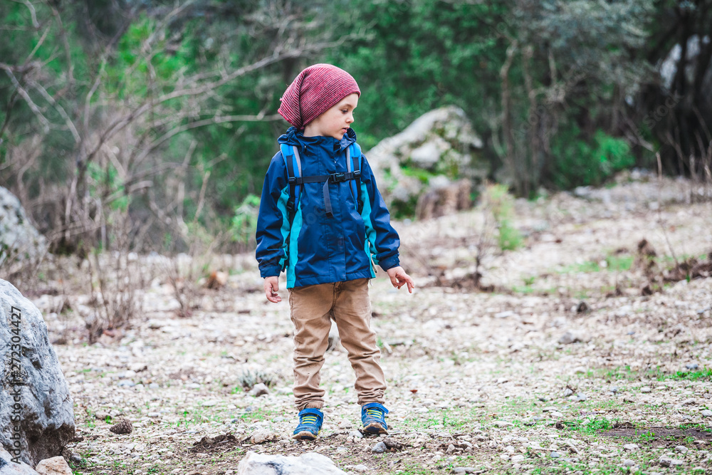 A boy with a backpack is walking along a forest path. A boy with a backpack is walking along a forest path.