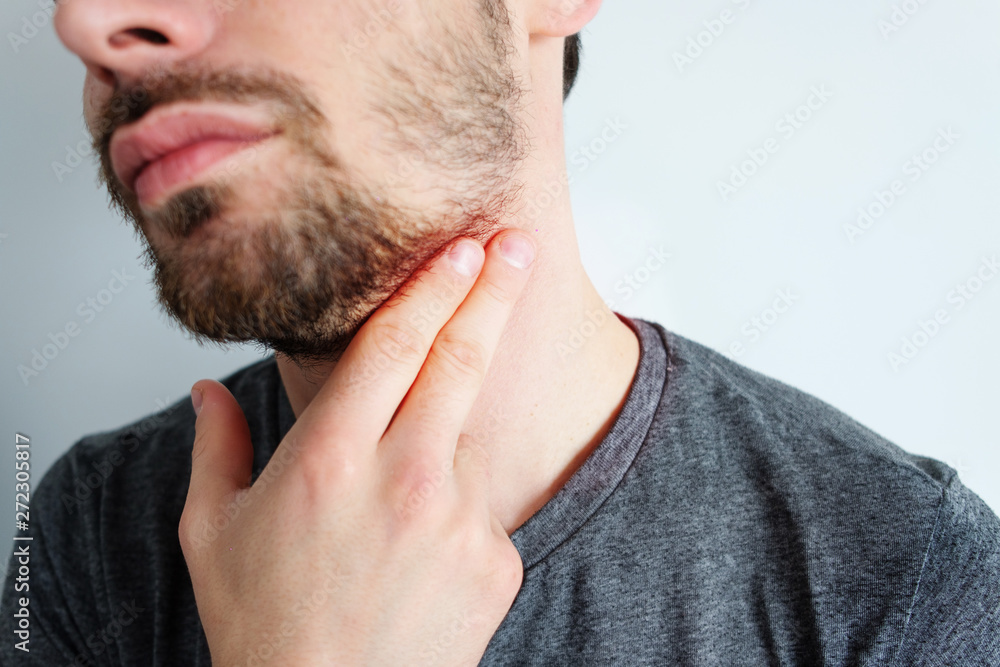 Obraz premium Photo of an attractive man, holds his hand on his wrist and neck, checks the pulse or heart rate, cares about his health, has a heartbeat, models on a white background. Pulse evaluation concept