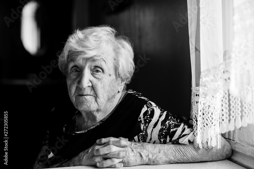 Elderly woman at his home. Black and white portrait of an old grandma.