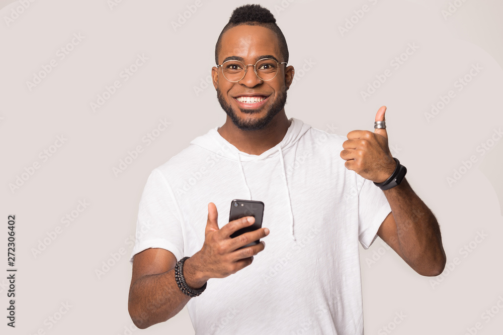 African guy happy smartphone user showing thumbs up studio shot African guy happy smartphone user showing thumbs up studio shot