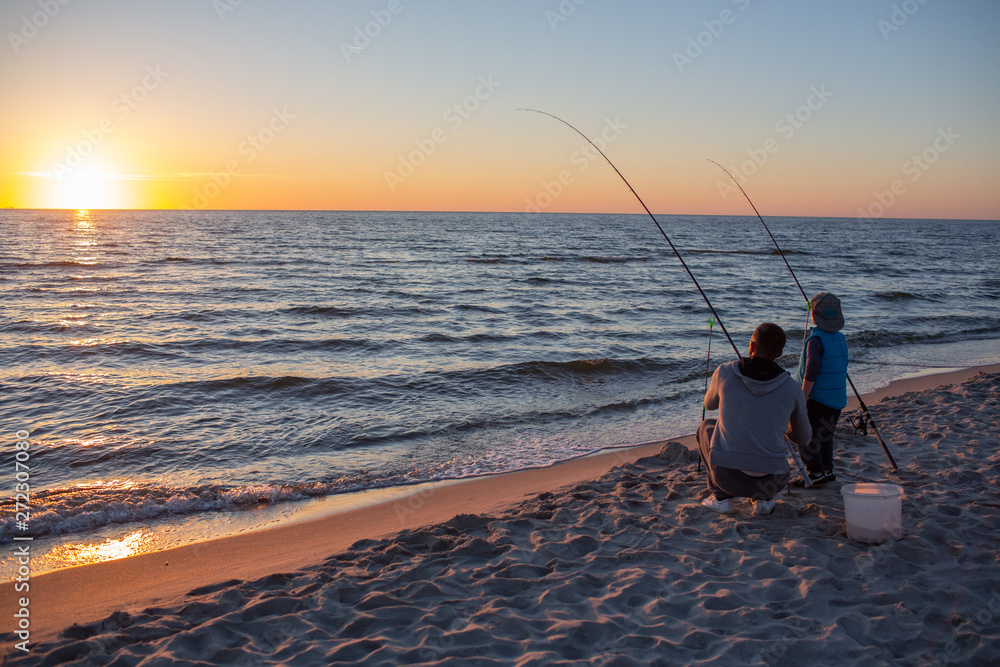 father and son catch fish on the Baltic coast at sunset