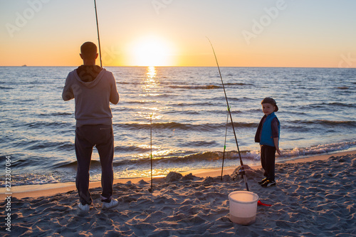 father and son catch fish on the Baltic coast at sunset