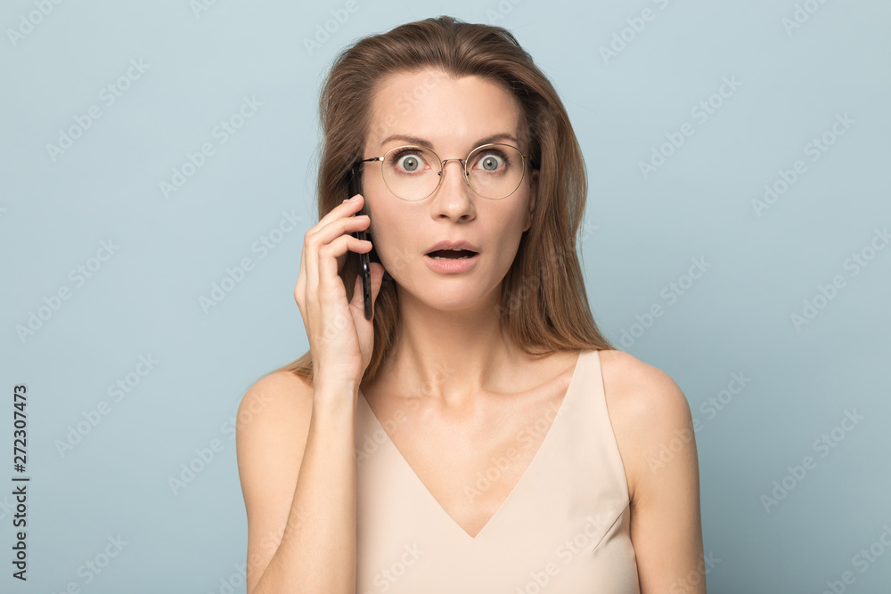Shocked young woman talking on phone, hearing unexpected news Shocked young woman talking on phone, hearing unexpected news