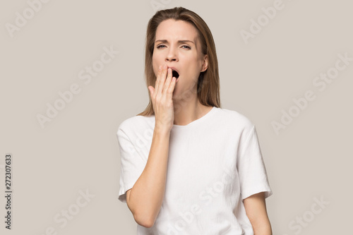 Fotografie Tired sleepy young woman yawning, covering mouth with hand