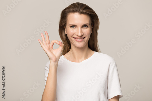 Confident smiling young woman, satisfied client showing ok gesture