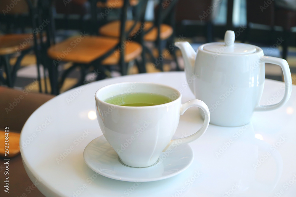 Closeup a cup of green tea with teapot served on a white round table 