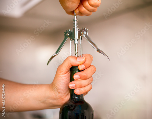 Woman opening bottle of wine with a corkscrew.