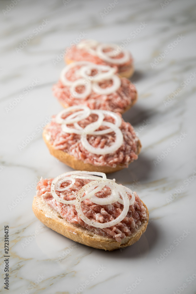 Deutsche Mettbrötchen mit rohen Schweine Mett, Brötchen, Butter, Zwiebeln, Pfeffer und Mett auf Marmor Arbeitsplatte in Küche Deutsche Mettbrötchen mit rohen Schweine Mett, Brötchen, Butter, Zwiebeln, Pfeffer und Mett auf Marmor Arbeitsplatte in Küche