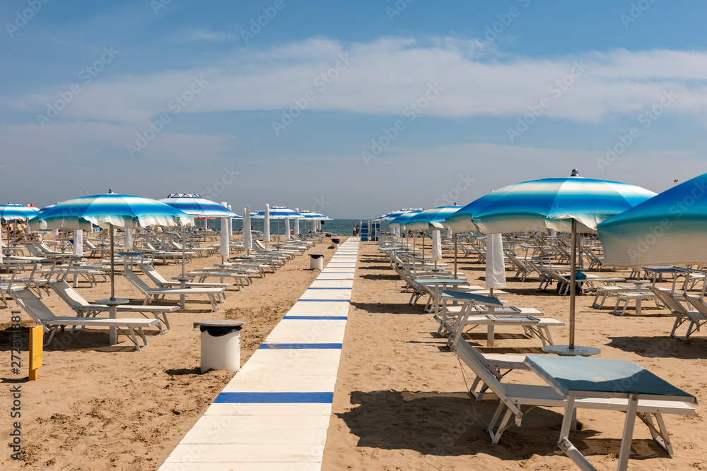 Striped sun umbrellas, sun beds, beach, Rimini, Italy.