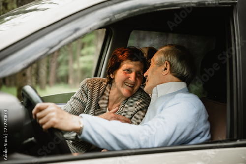 Happy elderly couple inside modern car. Seniors travelling together in car. Smiled and active retirees having date and romance inside new car. Happy aged family concept © Vadym