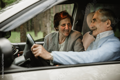 Happy elderly couple inside modern car. Seniors travelling together in car. Smiled and active retirees having date and romance inside new car. Happy aged family concept