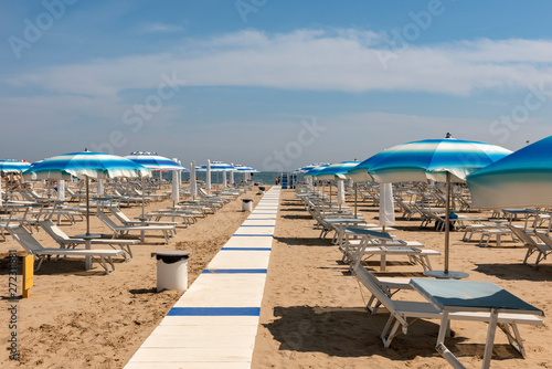 Striped sun umbrellas, sun beds, beach, Rimini, Italy.