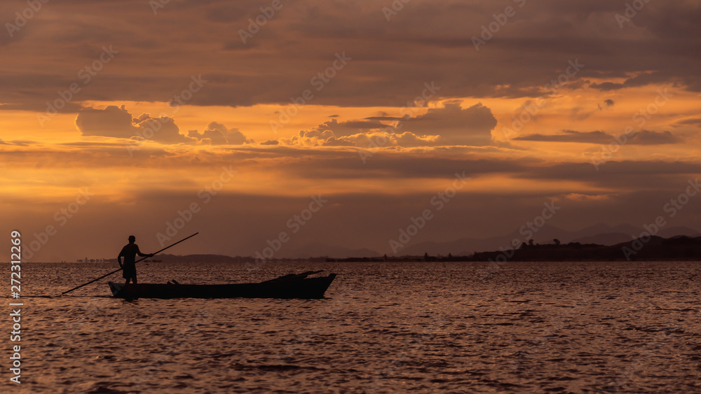 silhouette of fisherman on beach at sunset