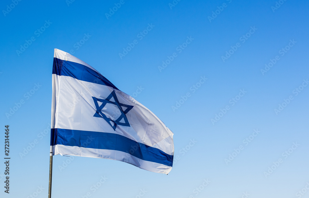 Fototapeta premium Israeli flag evolving on a wind on empty blue sky background 