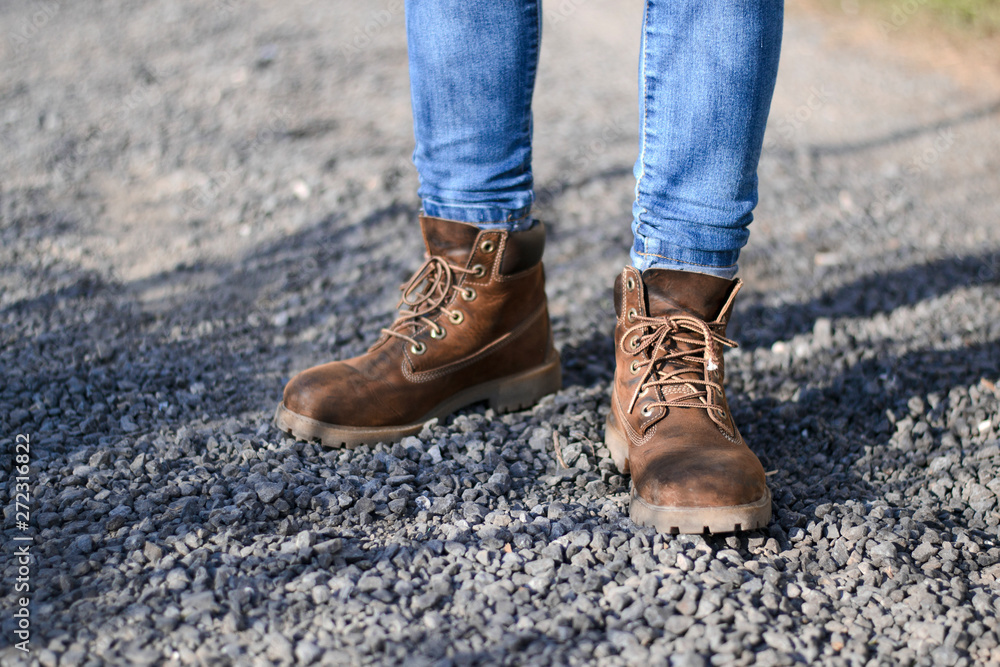 traveler in old hiking yellow boots standing on mountain road with stones traveler in old hiking yellow boots standing on mountain road with stones