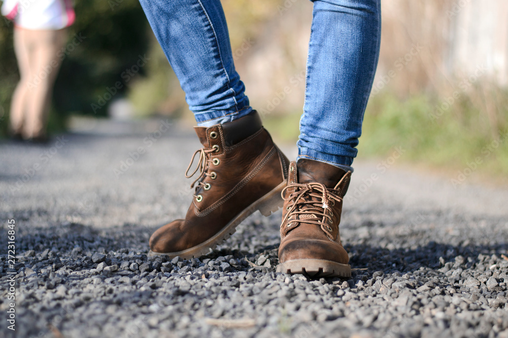 traveler in old hiking yellow boots standing on mountain road with stones traveler in old hiking yellow boots standing on mountain road with stones