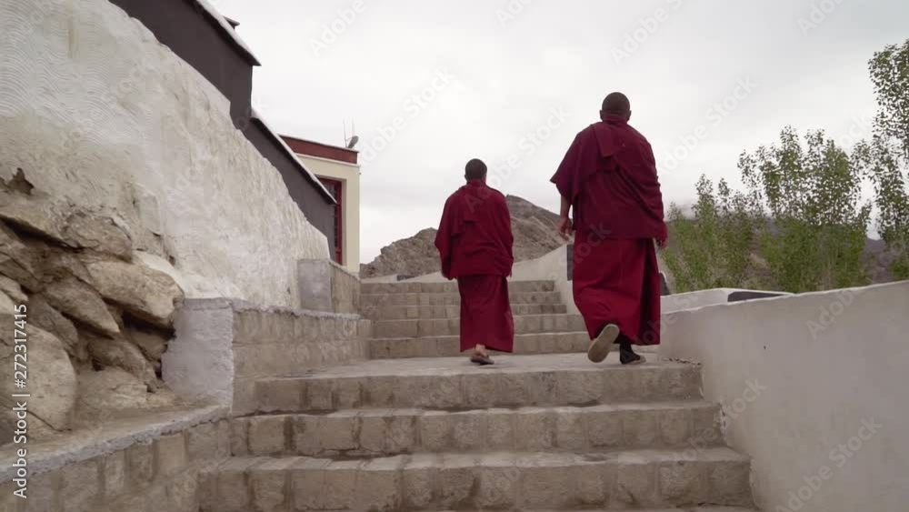 Slow motion handheld tracking shot as two Tibetan Buddhist monks walking up on the stairs, at the Thikse Gompa Monastery, in Ladakh, India Slow motion handheld tracking shot as two Tibetan Buddhist monks walking up on the stairs, at the Thikse Gompa Monastery, in Ladakh, India