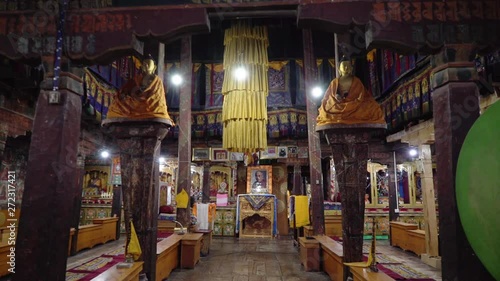 Slow motion push in wide shot in a Buddhist prayer room, with colourful flag decoration and a photo of the Dalai Lama photo