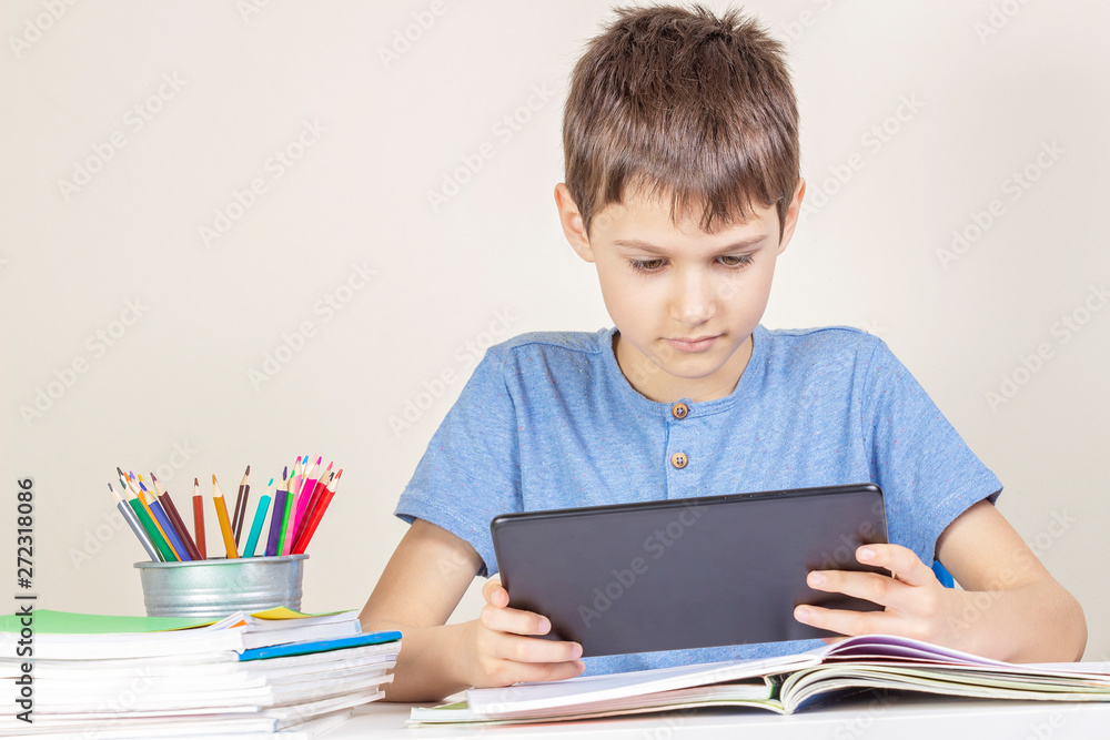 Kid with tablet computer sitting at table with books notebooks Kid with tablet computer sitting at table with books notebooks