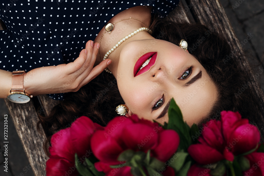 Close up flat lay, top view portrait of young beautiful confident woman with red lips makeup, wearing trendy pearl earrings, necklace, wrist watch, polka dot dress