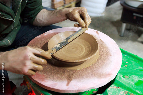 the master measures with a ruler the width of the plate, made to order from red clay. The product is made on a potter's wheel, on a sheet of chipboard for better removal and further drying. reportage.