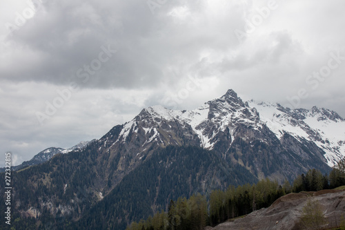 Panorama of an alpine landscape with high mountains, green meadows and trees in spring with snow in Austrian Alps © 2199_de