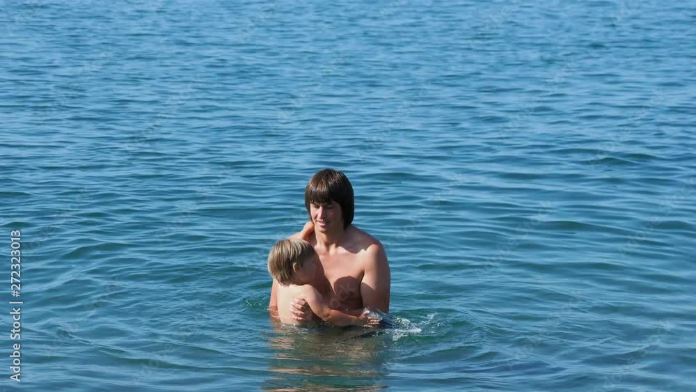 Father with son swimming In sea. Man with toddler are playing in water waves. Family leisure activity. Father with son swimming In sea. Man with toddler are playing in water waves. Family leisure activity.