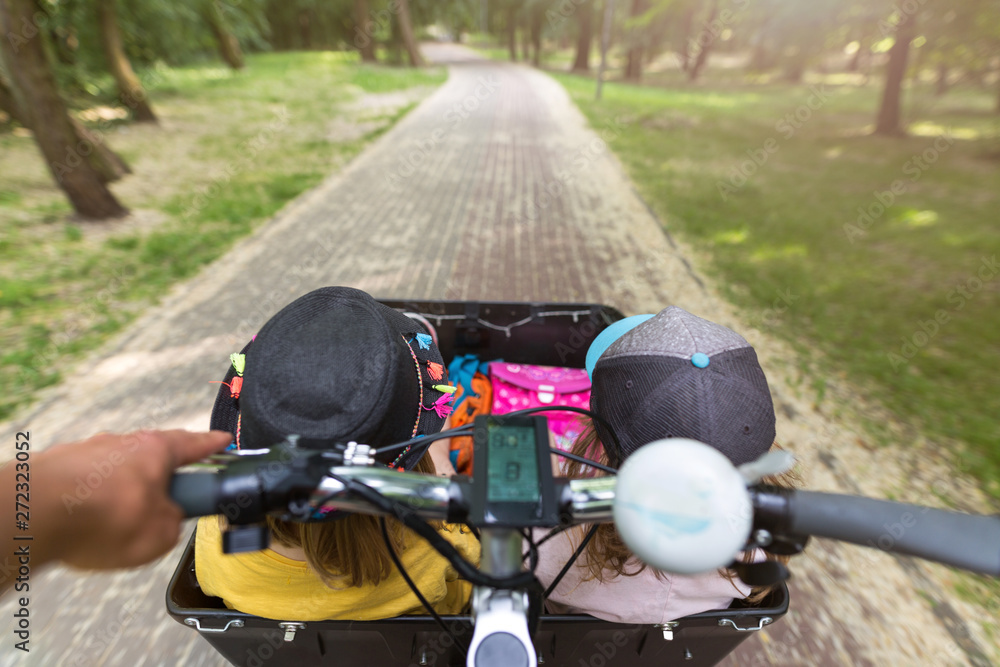 Two little girls riding in a cargo bike on their way to kindergarten Two little girls riding in a cargo bike on their way to kindergarten