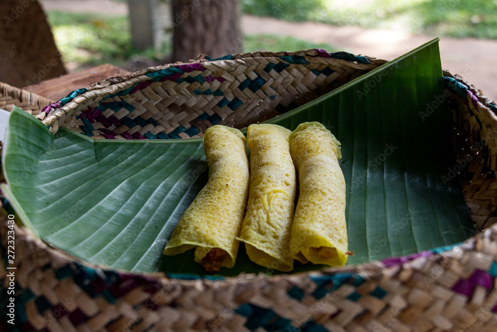 Obraz premium Sweet pancakes served on a banana leaf in a knitted basket. Sri Lankan breakfast.