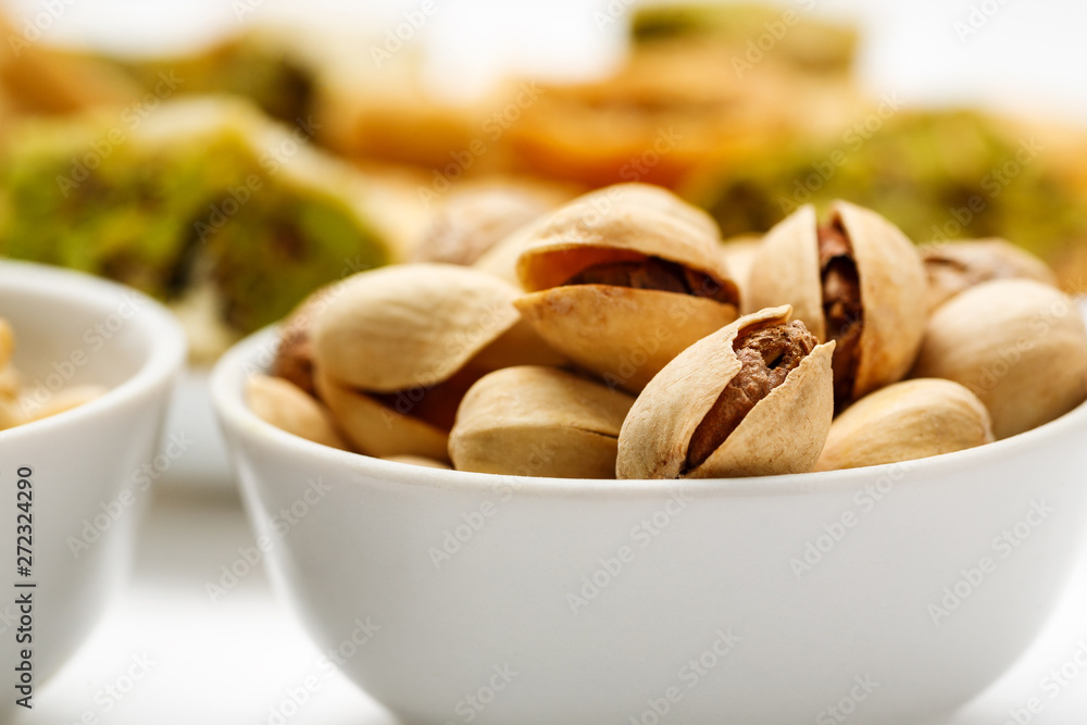 Pistachio in ceramic bowl with traditional oriental sweets in the background, close-up Pistachio in ceramic bowl with traditional oriental sweets in the background, close-up