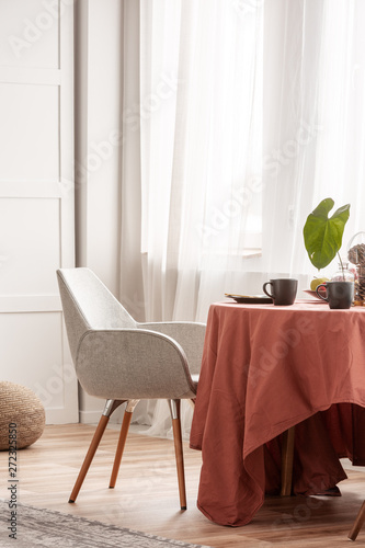 Stylish grey chairs at dining table covered with long tablecloth