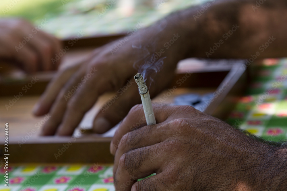 Obraz premium people playing backgammon and the man drinking cigarette with his hairy old hand.