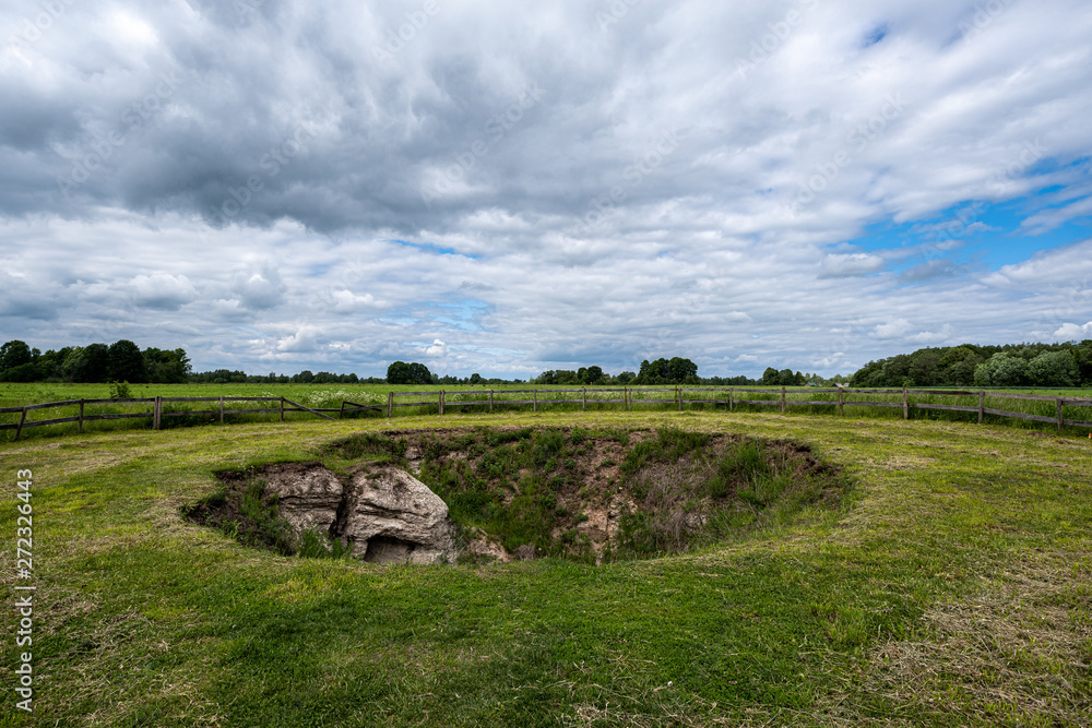 archeological pit cave in the ground in meadow
