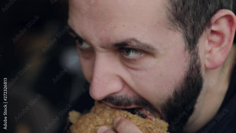 Close up face young man eating a hamburger food hungry lifestyle lunch meat potato sandwich snack tasty young calories food uhealthy adult cafe caucasian chicken crispy slow motion Close up face young man eating a hamburger food hungry lifestyle lunch meat potato sandwich snack tasty young calories food uhealthy adult cafe caucasian chicken crispy slow motion