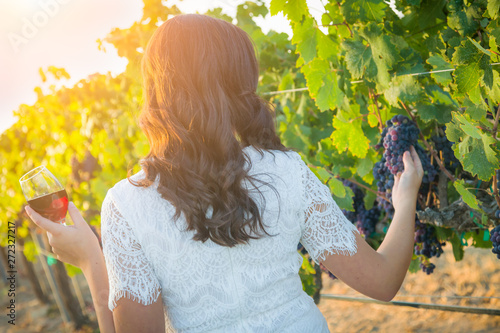 Young Adult Woman Enjoying Glass of Wine Tasting Walking In The Vineyard photo
