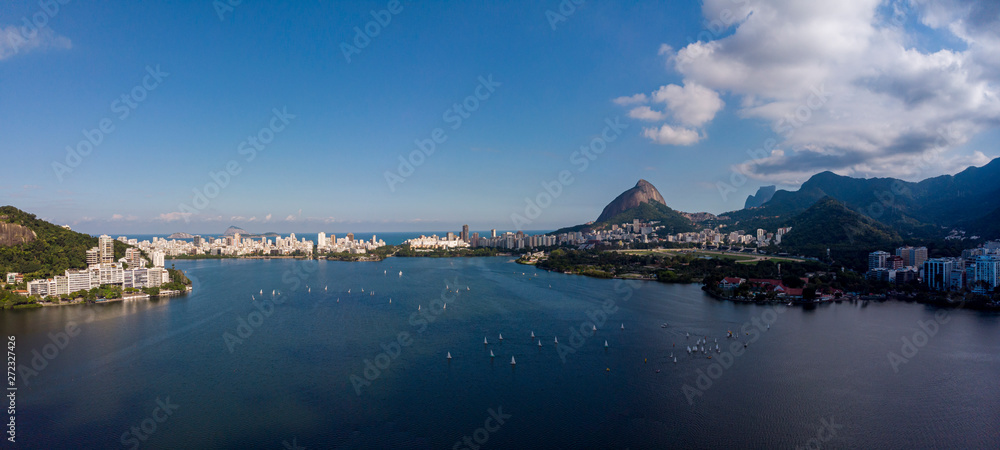 Aerial panoramic view of the city lake Lagoa Rodrigo de Freitas in Rio de Janeiro on a bright day with a sailboat race while clouds coming in on a bright day with blue sky