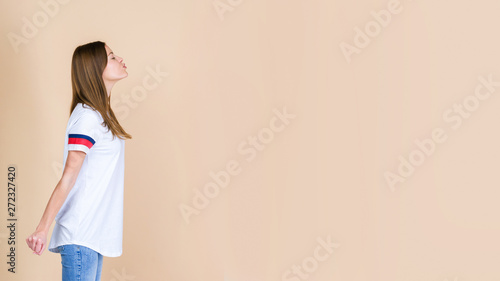 Profile of charming young adult woman waiting kiss standing isolated on pastel beige background photo