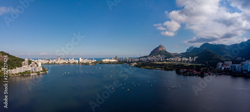 Aerial panoramic view of the city lake Lagoa Rodrigo de Freitas in Rio de Janeiro on a bright day with a sailboat race while clouds coming in on a bright day with blue sky