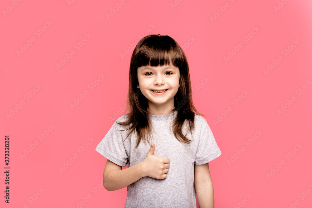Ready to school. Cheerful little girl looking up with smile while standing against pink background. Education, gesture and school concept - happy and smiling confident little girl showing finger up Ready to school. Cheerful little girl looking up with smile while standing against pink background. Education, gesture and school concept - happy and smiling confident little girl showing finger up