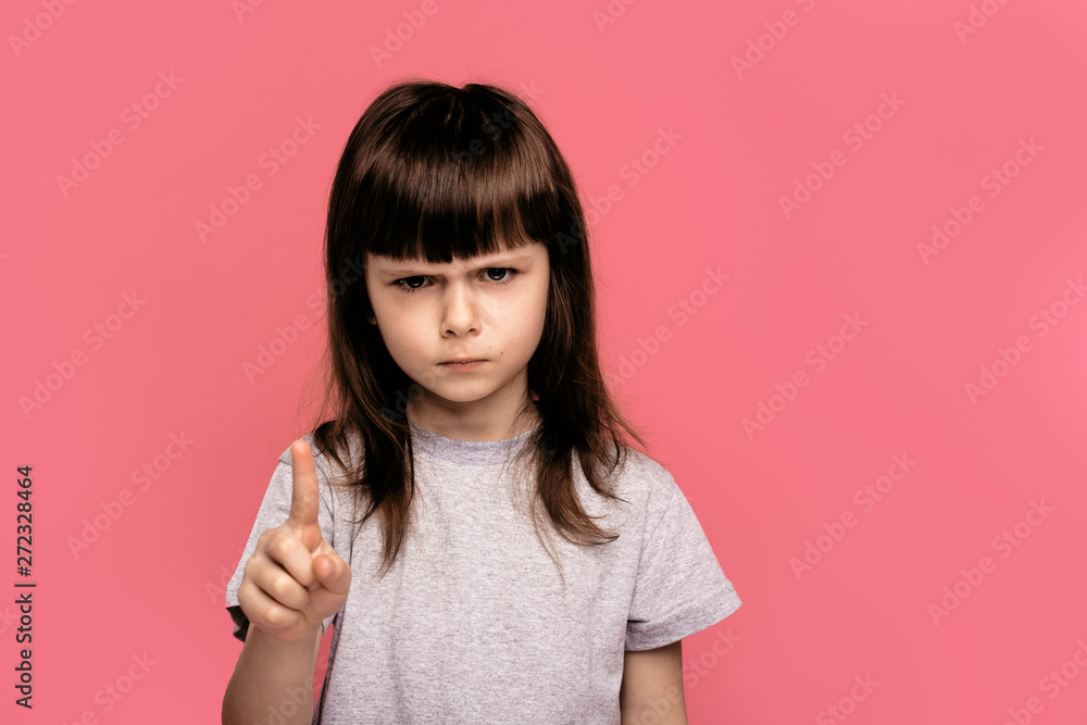 Annoyed little girl with bad attitude making stop gesture with her palm outward, saying no, expressing denial or restriction. Negative human emotions, feelings, body language. Selective focus on hand Annoyed little girl with bad attitude making stop gesture with her palm outward, saying no, expressing denial or restriction. Negative human emotions, feelings, body language. Selective focus on hand