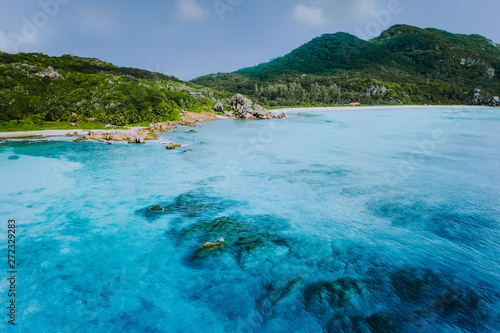 Tropical coastline of La Digue island with granite boulders and paradise beaches, view from the sea, Seychelles