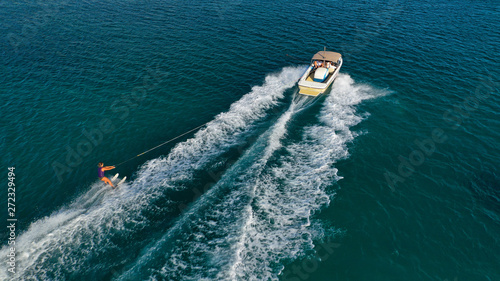 Aerial photo of man practicing high speed water ski towed by speed boat in deep blue sea © aerial-drone